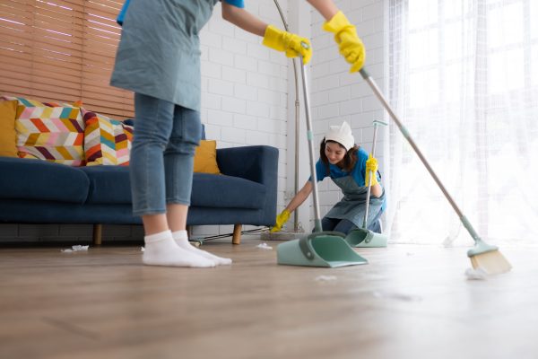 Cleaning service. Dark-haired woman wearing a white hat and yellow gloves cleaning the floor